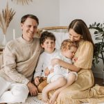 Happy family of four enjoying quality time together in a cozy, plant-filled room.